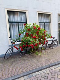 Photo of Bush with beautiful red roses and bicycles on city street