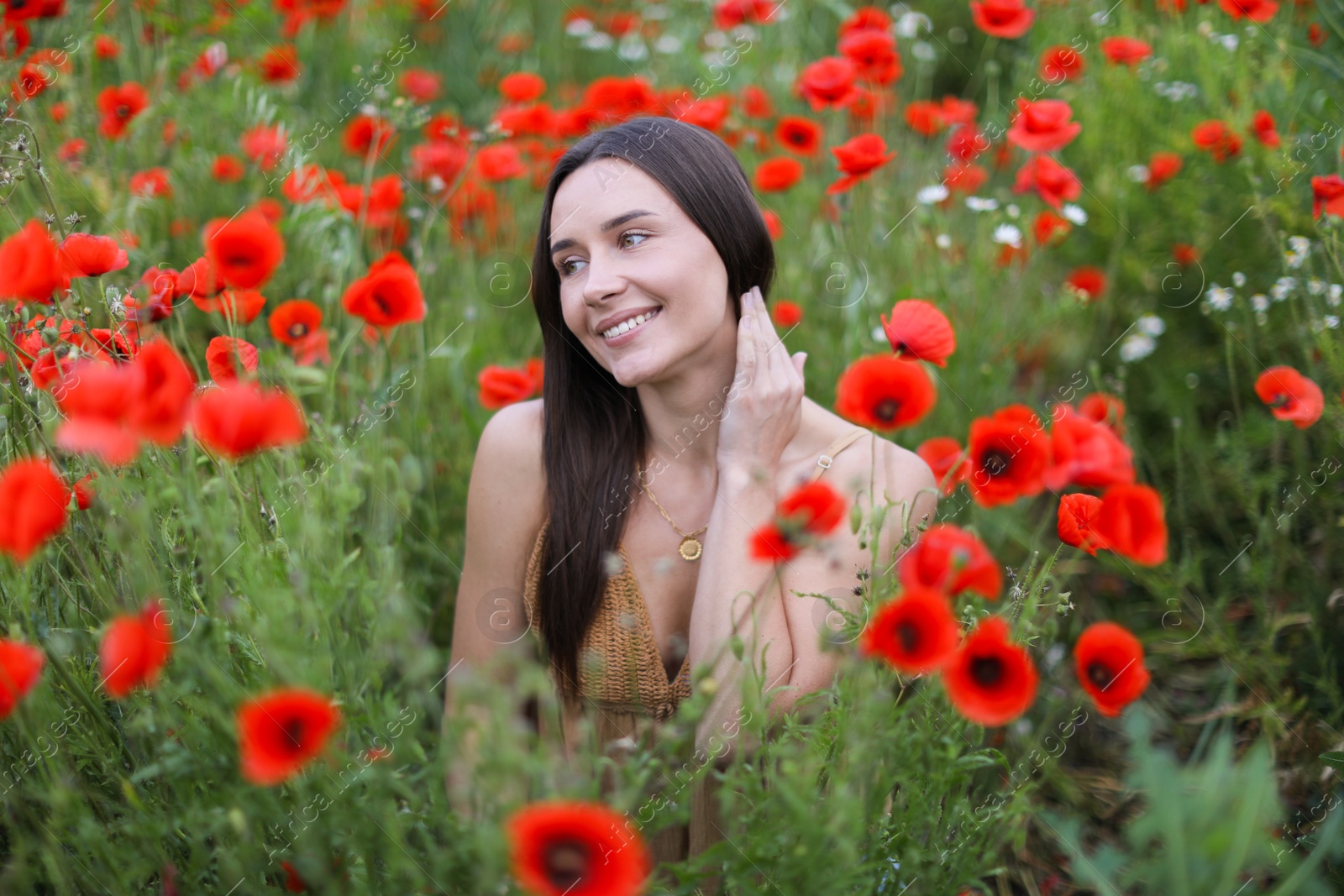 Smiling woman among red poppy flowers in wildflower meadow Photo of Smiling woman among red poppy flowers in wildflower meadow