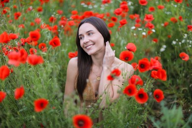 Photo of Smiling woman among red poppy flowers in wildflower meadow