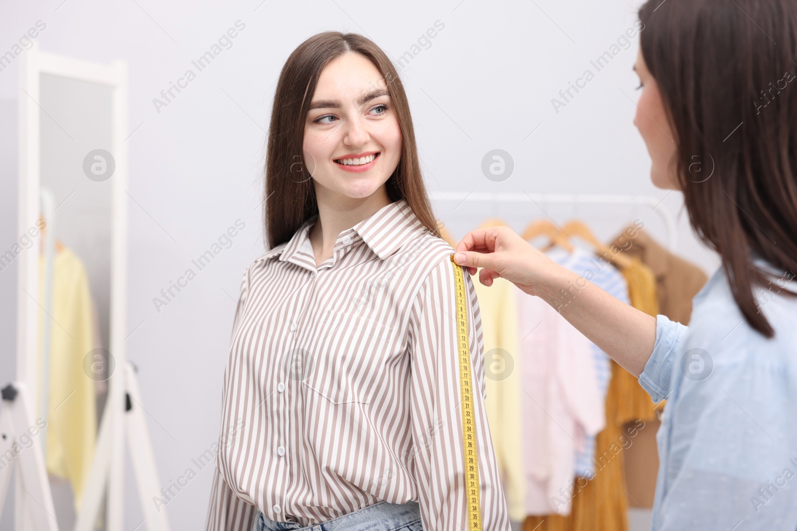Tailor measuring woman's arm with tape in atelier Photo of Tailor measuring woman's arm with tape in atelier