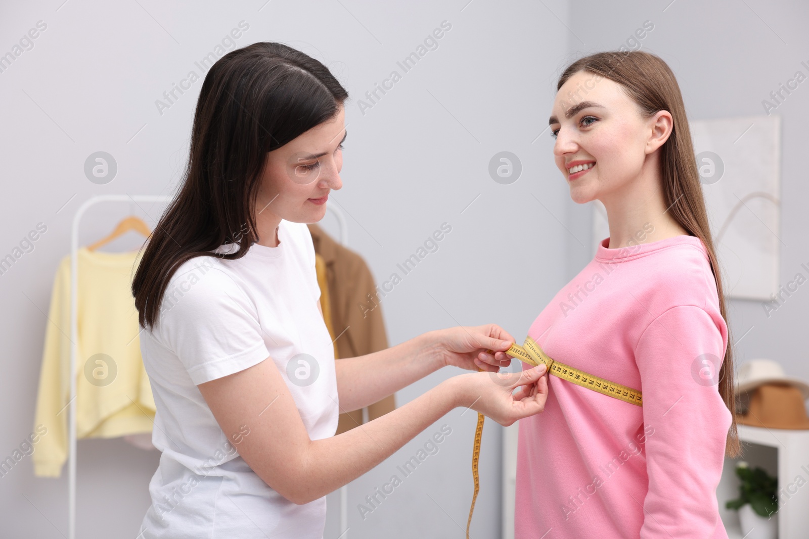 Photo of Tailor measuring woman's chest with tape in atelier