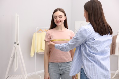 Photo of Tailor measuring woman's chest with tape in atelier