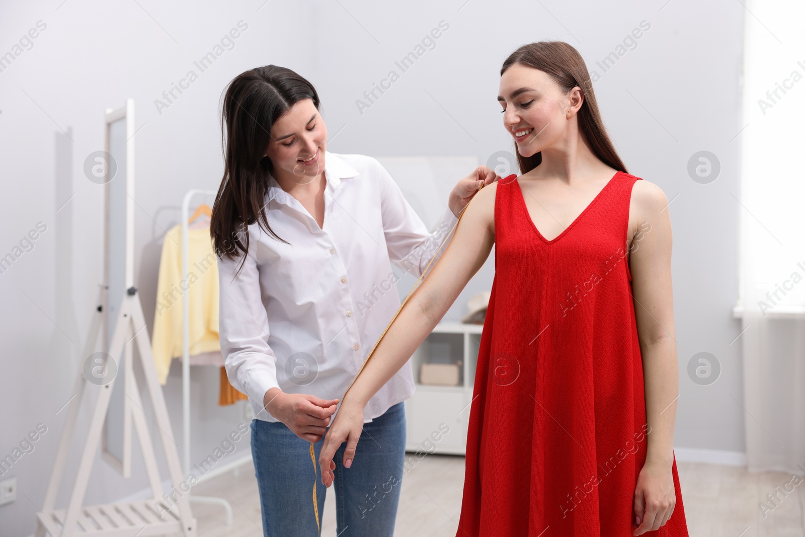 Tailor measuring woman's arm with tape in atelier Photo of Tailor measuring woman's arm with tape in atelier