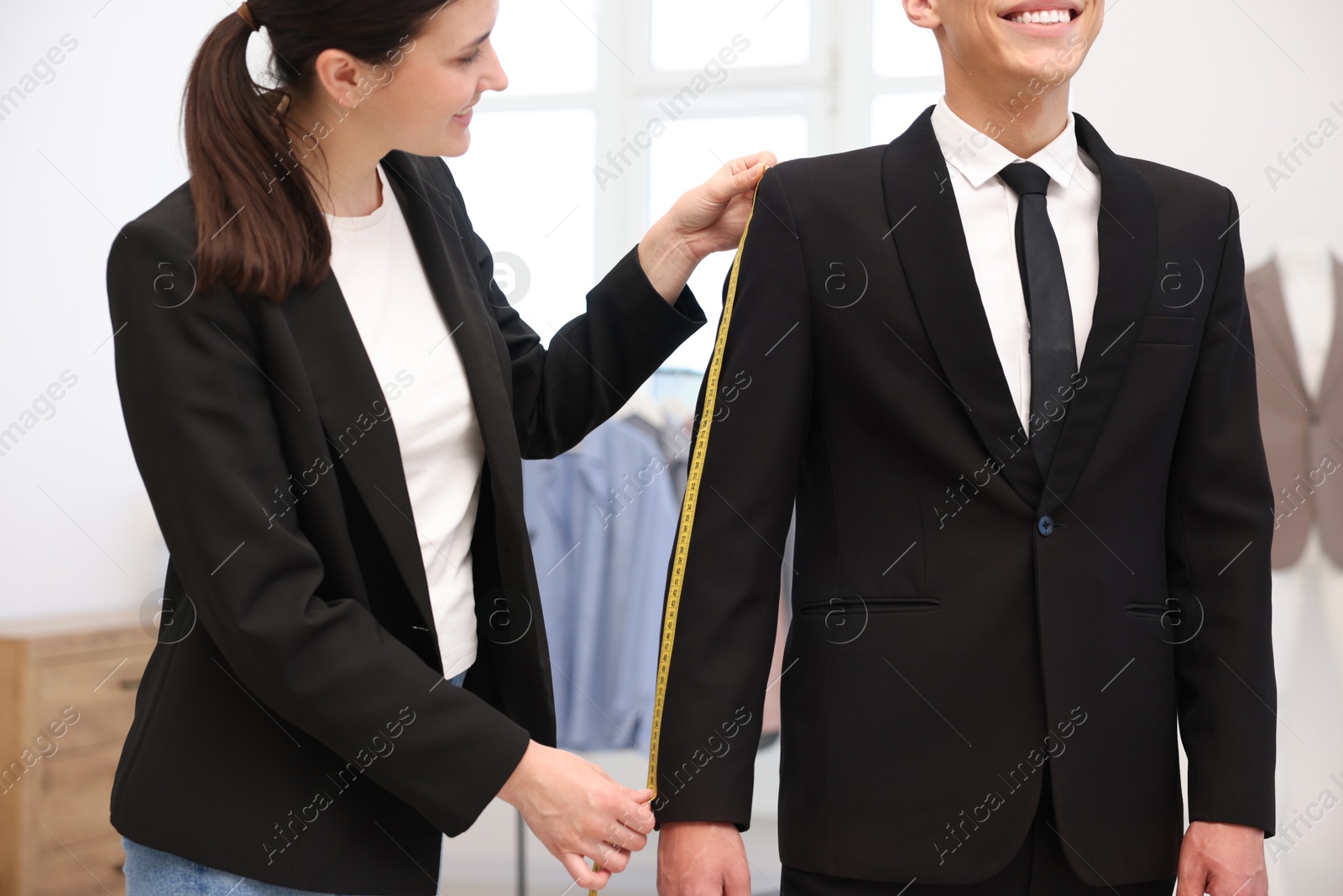 Tailor measuring jacket on man in atelier, closeup Photo of Tailor measuring jacket on man in atelier, closeup