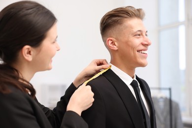 Photo of Tailor measuring jacket on man in atelier