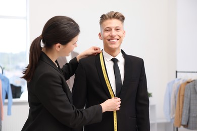 Photo of Tailor measuring jacket on man in atelier