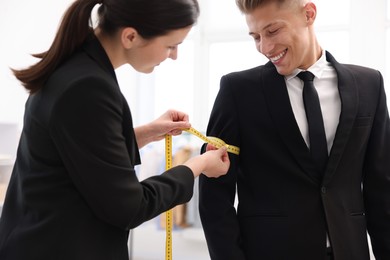 Photo of Tailor measuring jacket on man in atelier