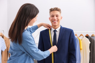 Photo of Tailor measuring jacket on man in atelier