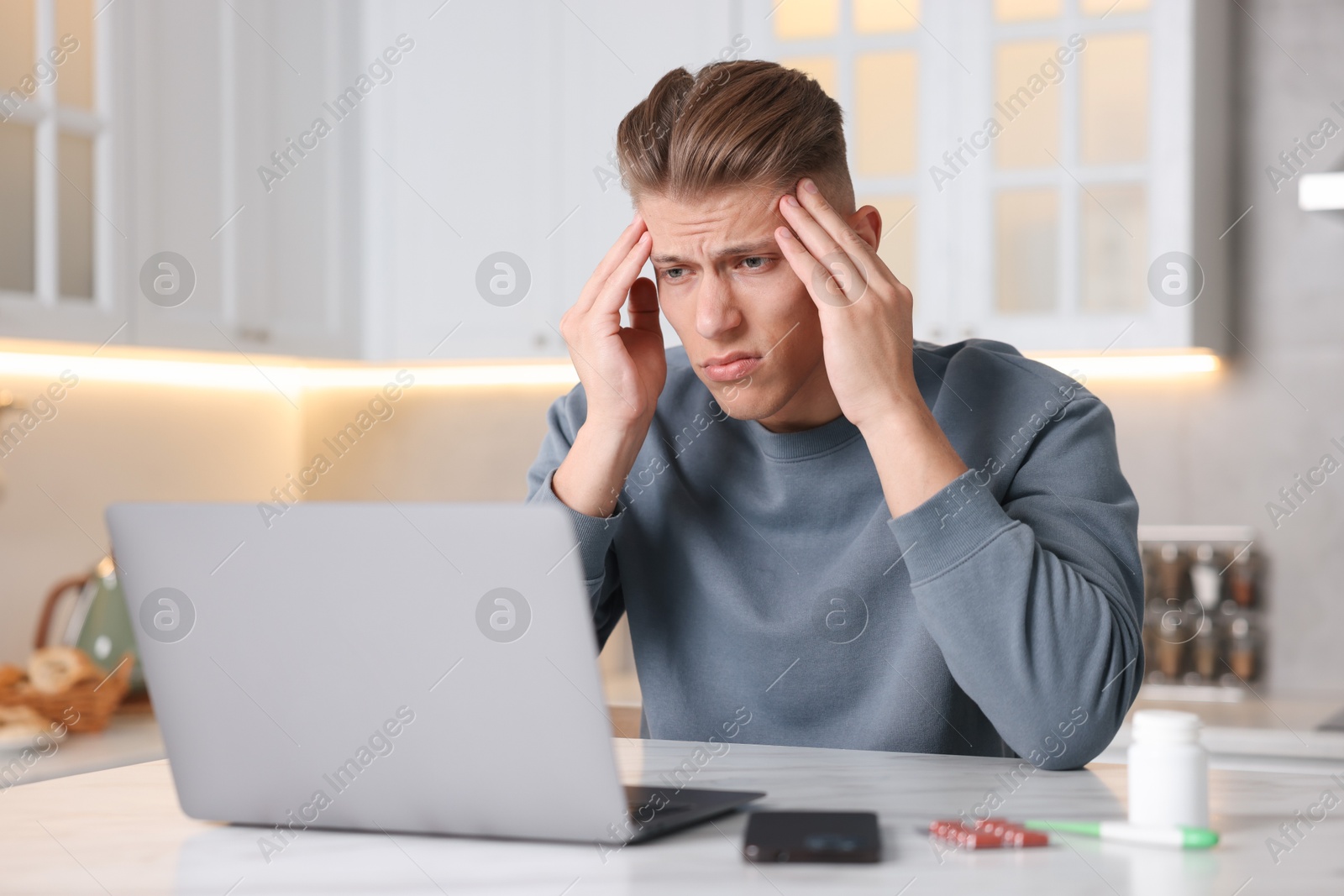 Sick man having online consultation with doctor via laptop at white marble table in kitchen Photo of Sick man having online consultation with doctor via laptop at white marble table in kitchen
