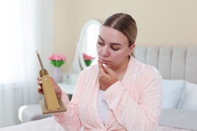 Photo of Woman with acne problem looking in mirror at home