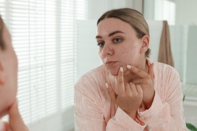 Photo of Woman popping pimple near mirror in bathroom. Acne problem