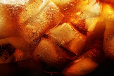 Photo of Refreshing cola with ice as background, macro view