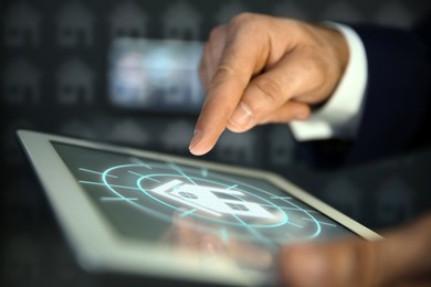 Image of Real estate agent using tablet computer, closeup. House icon on device screen
