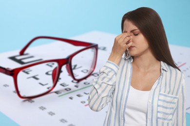 Image of Woman with eyesight problems, glasses and vision test chart on light blue background