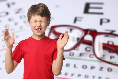 Image of Little boy with eyesight problems, glasses and vision test chart