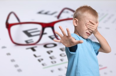 Image of Little boy with eyesight problems, glasses and vision test chart