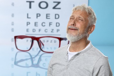 Image of Senior man with eyesight problems, glasses and vision test chart on light blue background