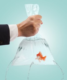 Image of Woman holding leaking plastic bag with goldfish against light blue background, closeup. Water flowing out of holes