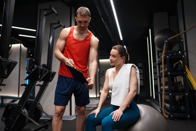 Photo of Young woman with professional personal trainer in gym