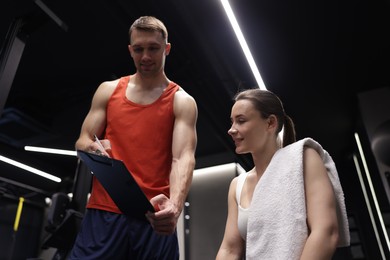 Photo of Young woman with professional personal trainer in gym