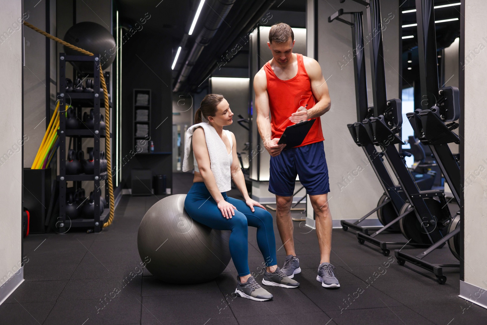 Young woman with professional personal trainer in gym Photo of Young woman with professional personal trainer in gym