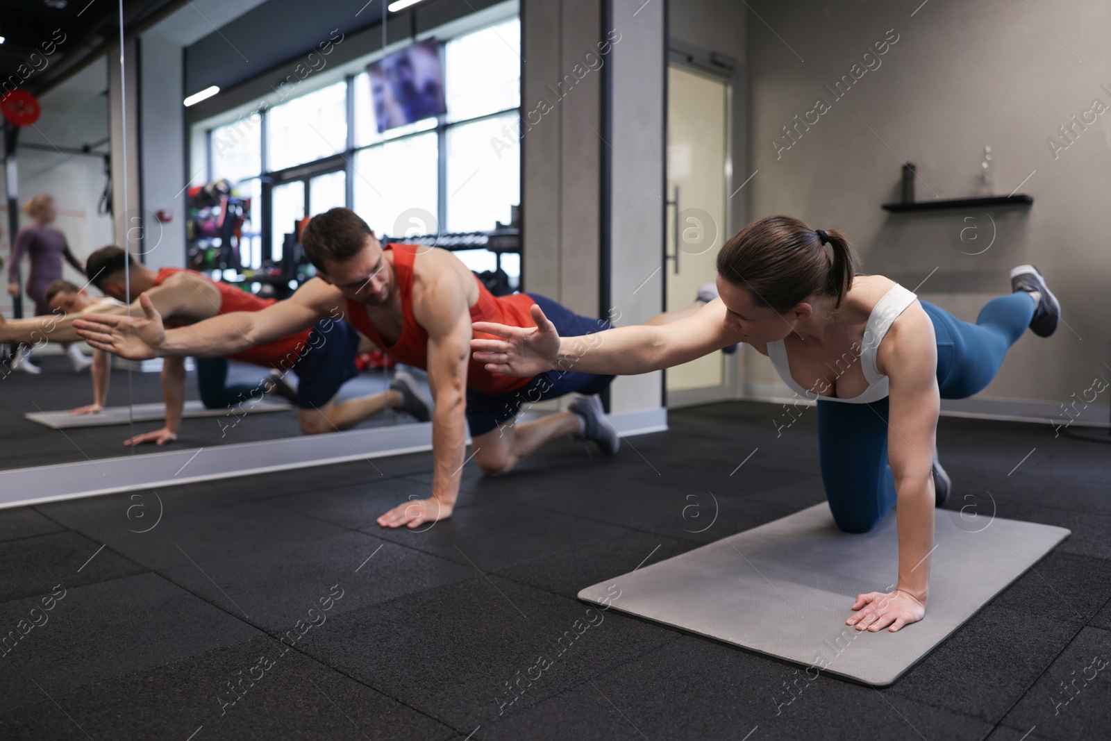 Young woman exercising on fitness mat with professional personal trainer in gym Photo of Young woman exercising on fitness mat with professional personal trainer in gym