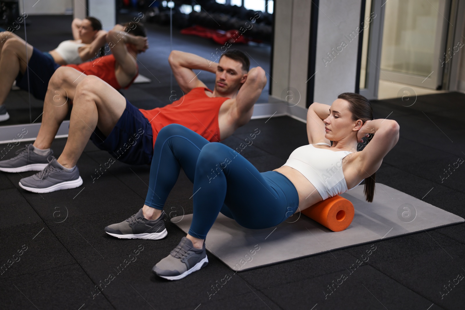 Young woman exercising on fitness mat with professional personal trainer in gym Photo of Young woman exercising on fitness mat with professional personal trainer in gym
