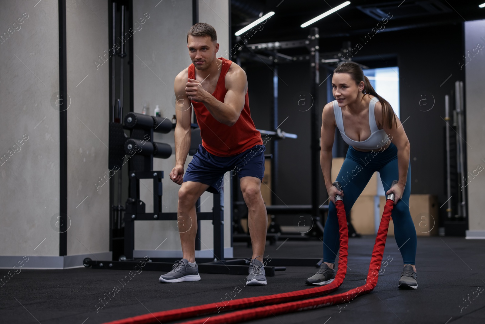 Young woman exercising with battle ropes and professional personal trainer in gym Photo of Young woman exercising with battle ropes and professional personal trainer in gym