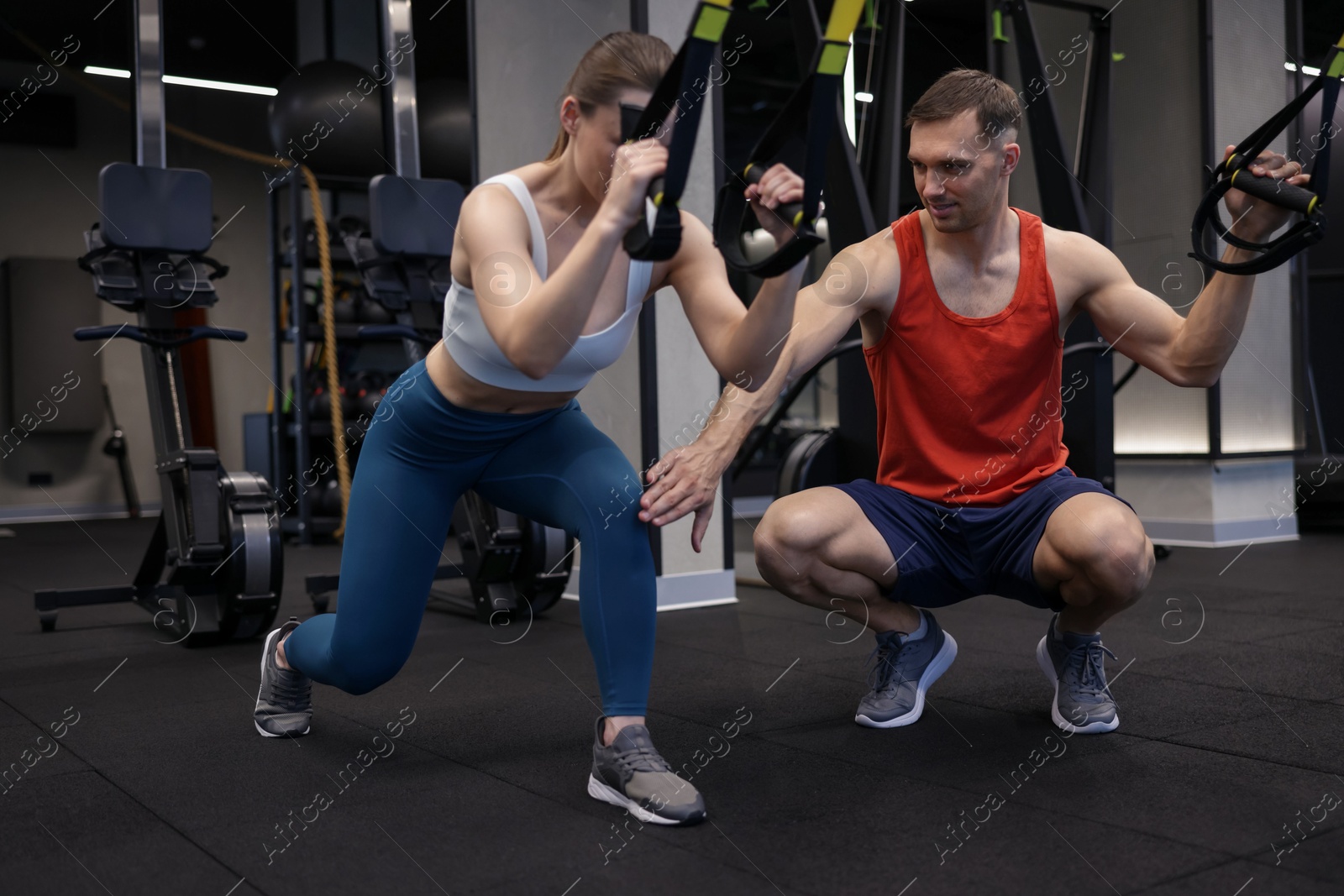 Young woman exercising with suspension trainers with professional personal coach in gym Photo of Young woman exercising with suspension trainers with professional personal coach in gym