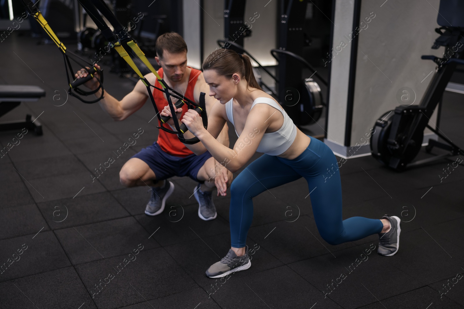 Young woman exercising with suspension trainers with professional personal coach in gym Photo of Young woman exercising with suspension trainers with professional personal coach in gym