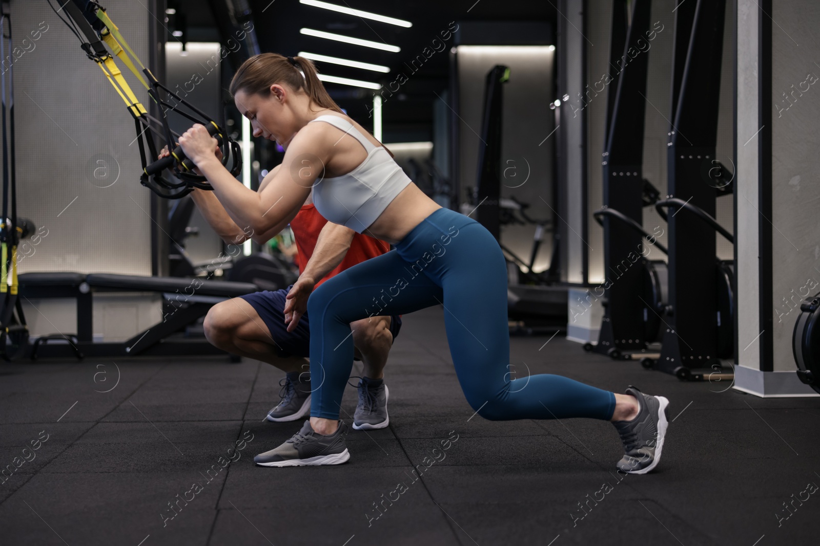 Young woman exercising with suspension trainers with professional personal coach in gym Photo of Young woman exercising with suspension trainers with professional personal coach in gym