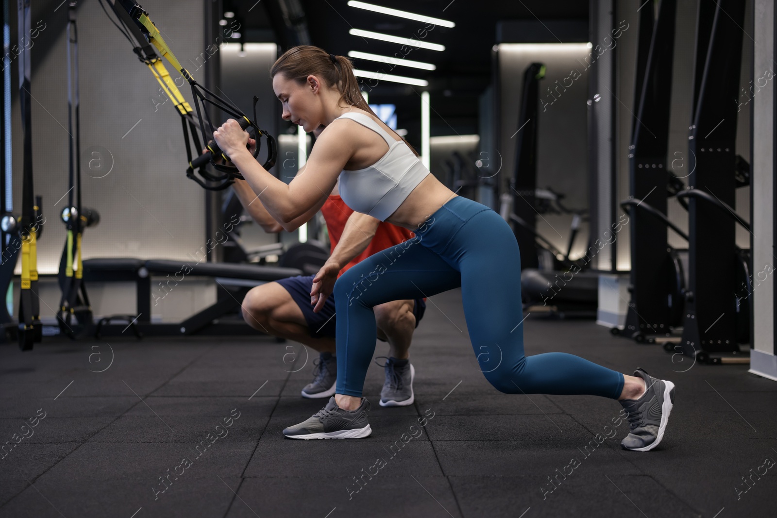 Young woman exercising with suspension trainers with professional personal coach in gym Photo of Young woman exercising with suspension trainers with professional personal coach in gym