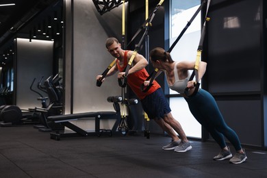 Photo of Young woman exercising with suspension trainers with professional personal coach in gym, space for text