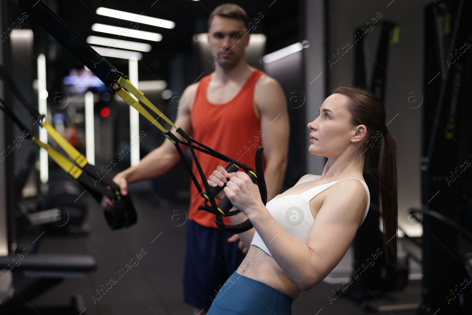 Young woman exercising with suspension trainers with professional personal coach in gym Photo of Young woman exercising with suspension trainers with professional personal coach in gym