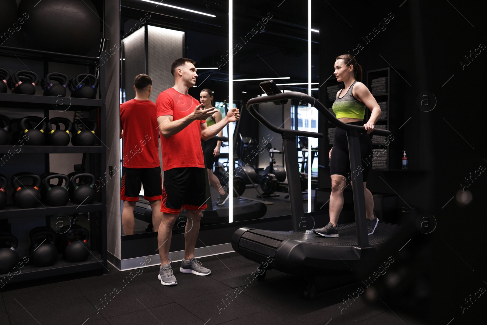 Young woman exercising on treadmill with professional personal trainer in gym Photo of Young woman exercising on treadmill with professional personal trainer in gym
