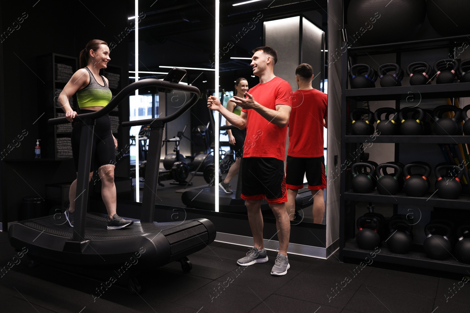 Young woman exercising on treadmill with professional personal trainer in gym Photo of Young woman exercising on treadmill with professional personal trainer in gym