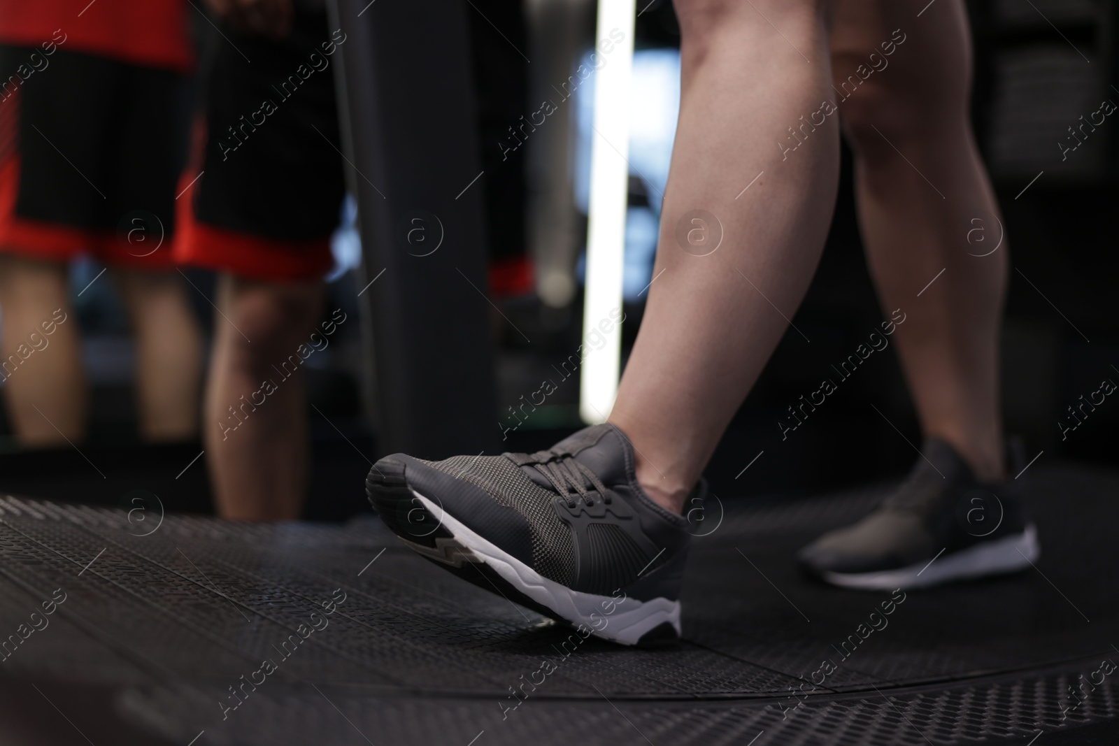 Young woman exercising on treadmill with professional personal trainer in gym, closeup Photo of Young woman exercising on treadmill with professional personal trainer in gym, closeup