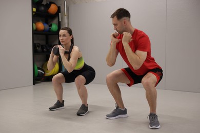 Photo of Young woman exercising with kettlebell with professional personal trainer in gym