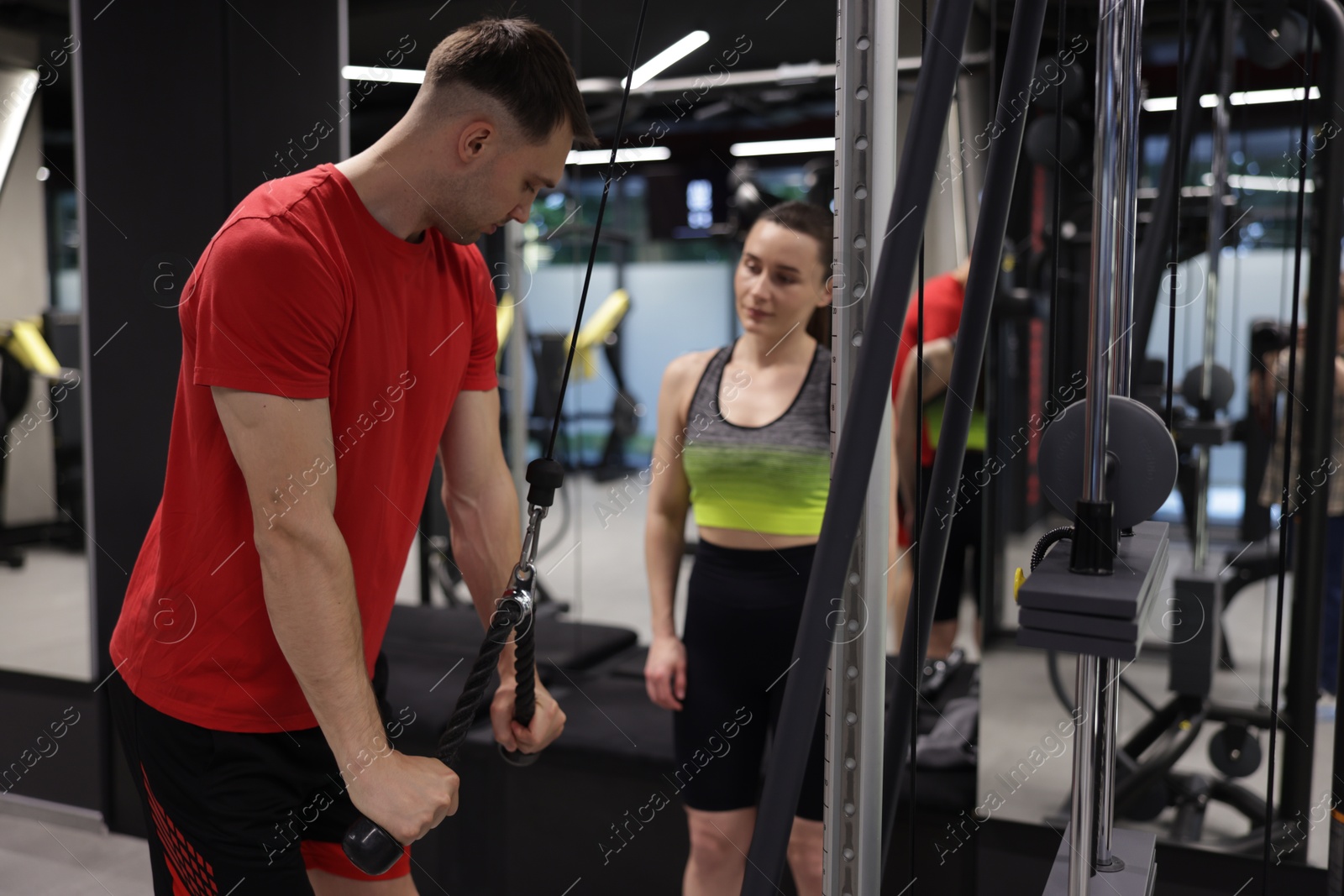 Professional personal trainer showing young woman how to exercise with lat pulldown machine in gym Photo of Professional personal trainer showing young woman how to exercise with lat pulldown machine in gym