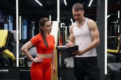 Photo of Young woman with professional personal trainer in gym