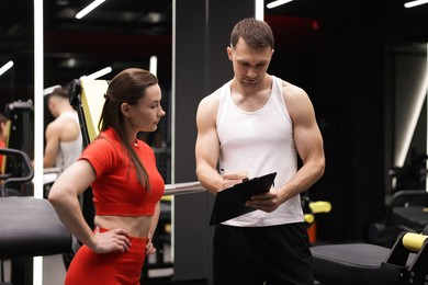 Photo of Young woman with professional personal trainer in gym