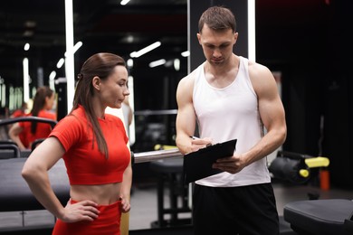 Photo of Young woman with professional personal trainer in gym