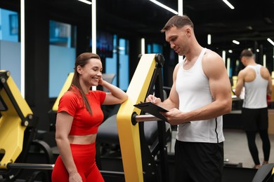 Photo of Young woman with professional personal trainer in gym