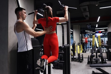 Photo of Young woman exercising with professional personal trainer in gym, back view. Space for text