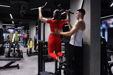 Photo of Young woman exercising with professional personal trainer in gym, back view. Space for text