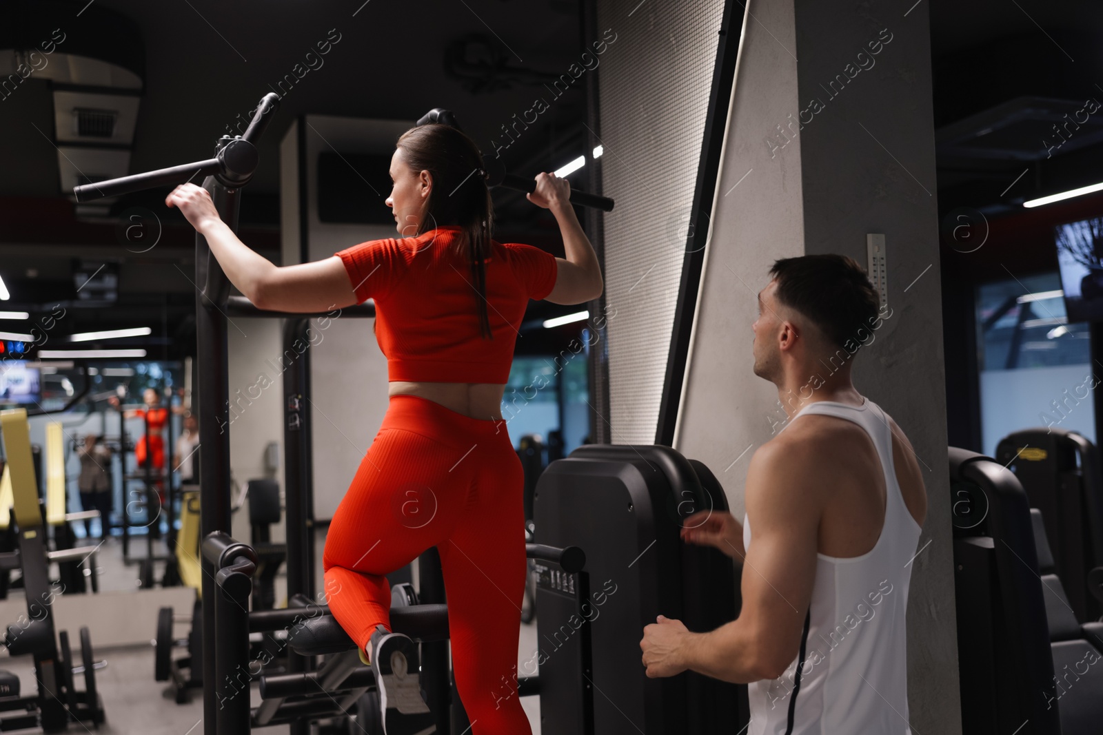 Young woman exercising with professional personal trainer in gym, back view Photo of Young woman exercising with professional personal trainer in gym, back view
