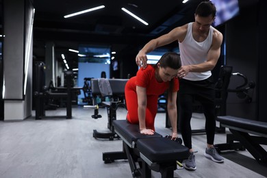 Photo of Young woman exercising with dumbbells with professional personal trainer in gym, space for text