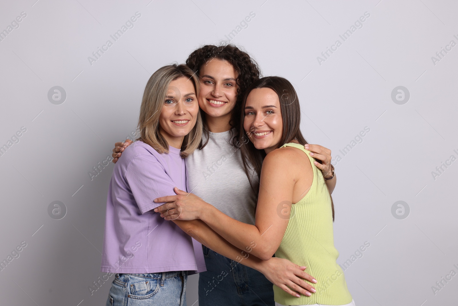 Portrait of happy friends hugging on grey background Photo of Portrait of happy friends hugging on grey background