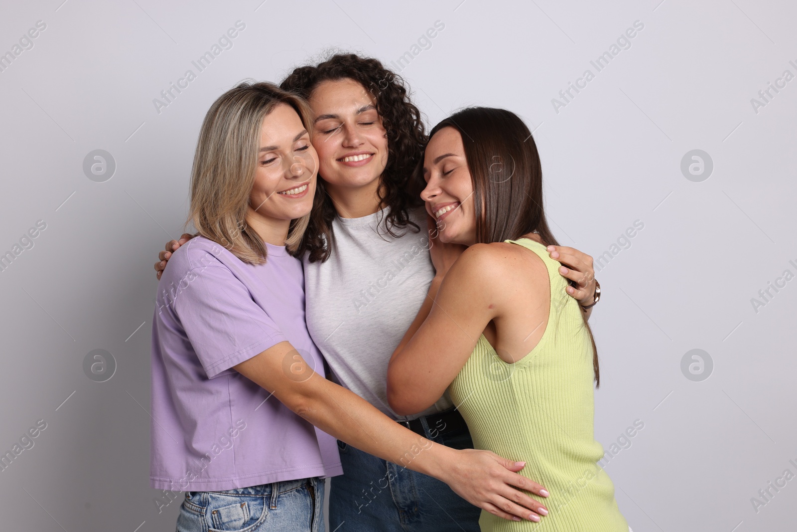 Happy friends hugging each other on grey background Photo of Happy friends hugging each other on grey background