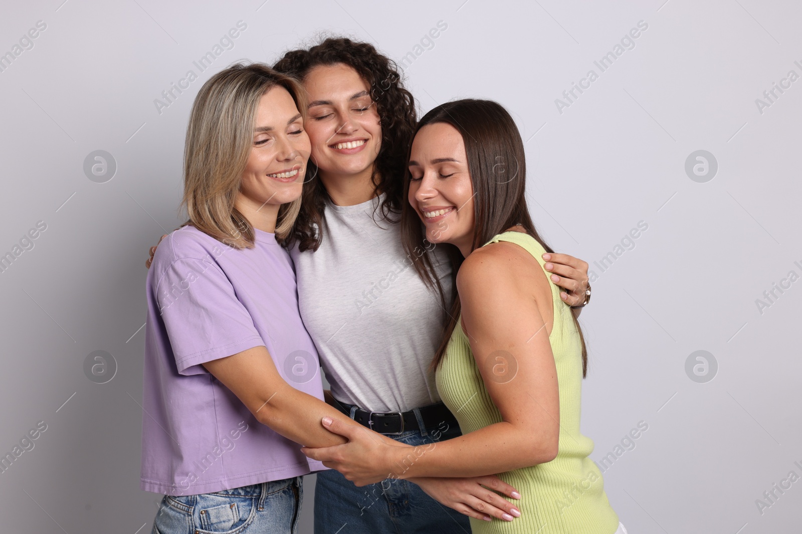 Happy friends hugging each other on grey background Photo of Happy friends hugging each other on grey background